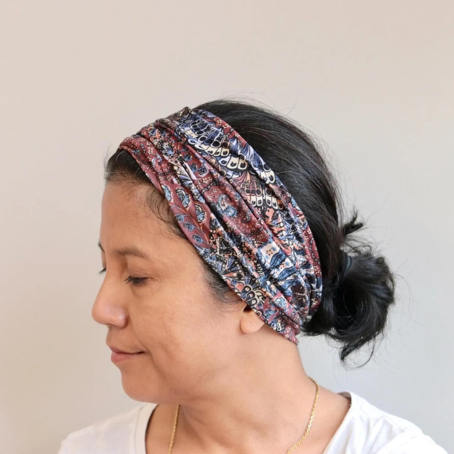 Woman wearing a patterned headband against a plain background