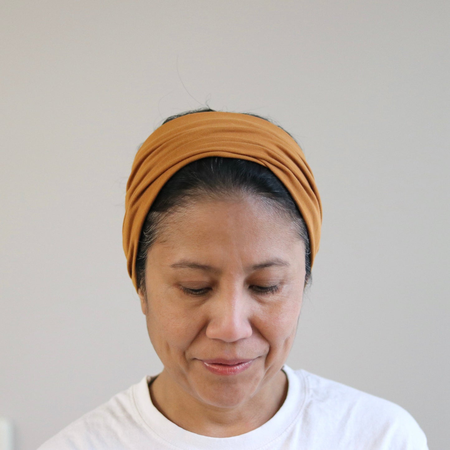Woman wearing a cooper brown headband against a plain background
