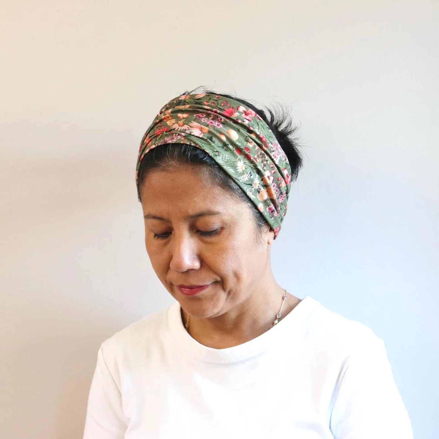 Woman wearing a floral headband against a plain background