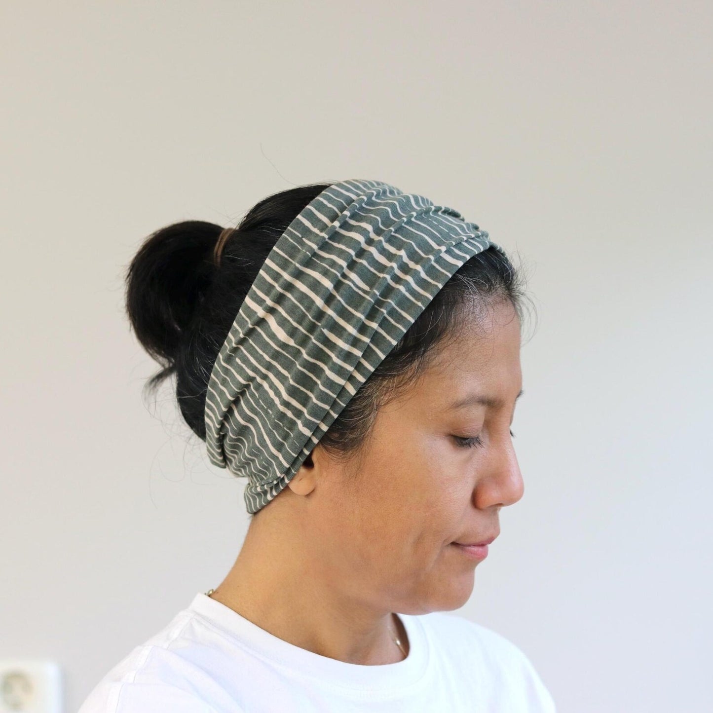 Woman wearing a green patterned headband against a plain background