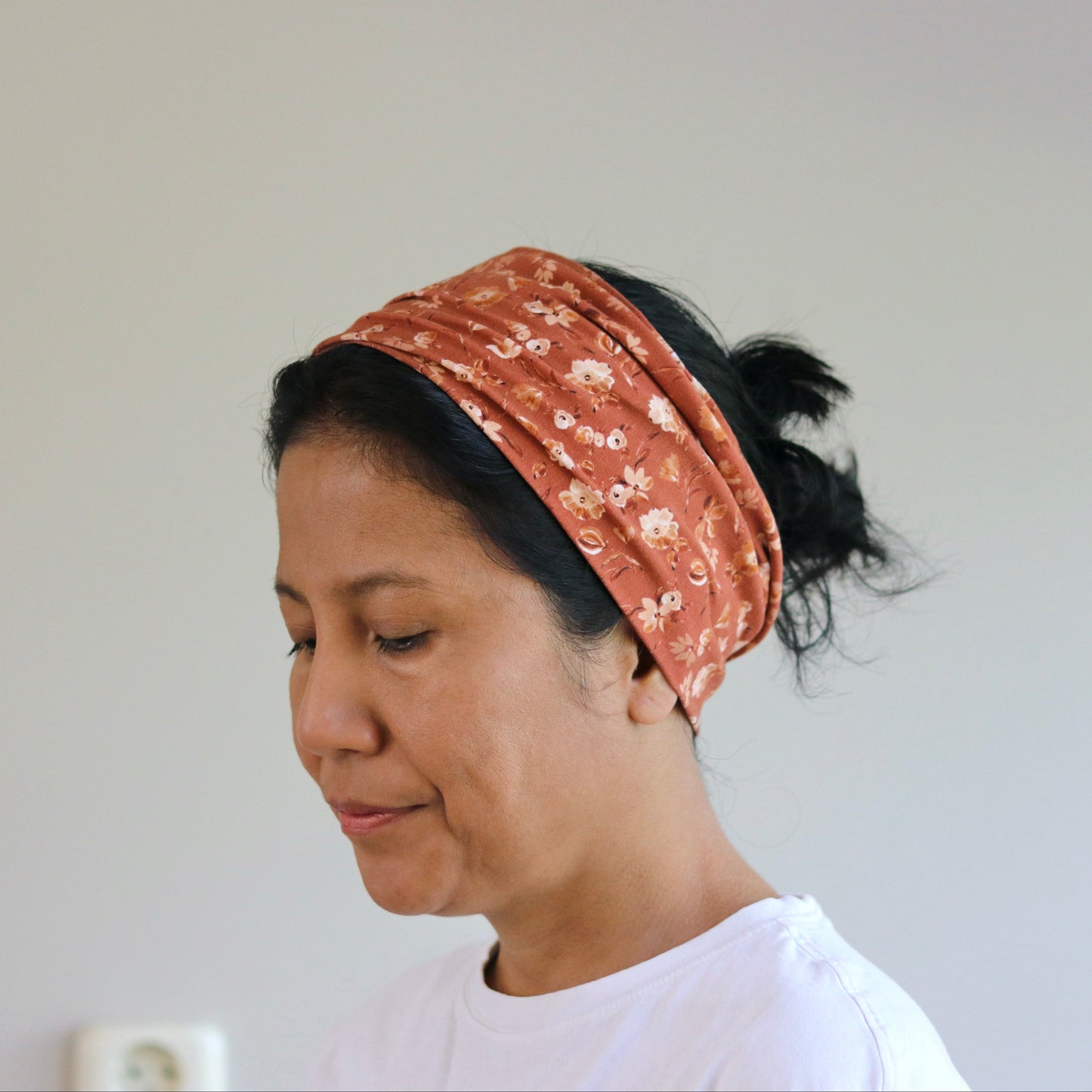 Woman wearing a patterned headband against a plain background