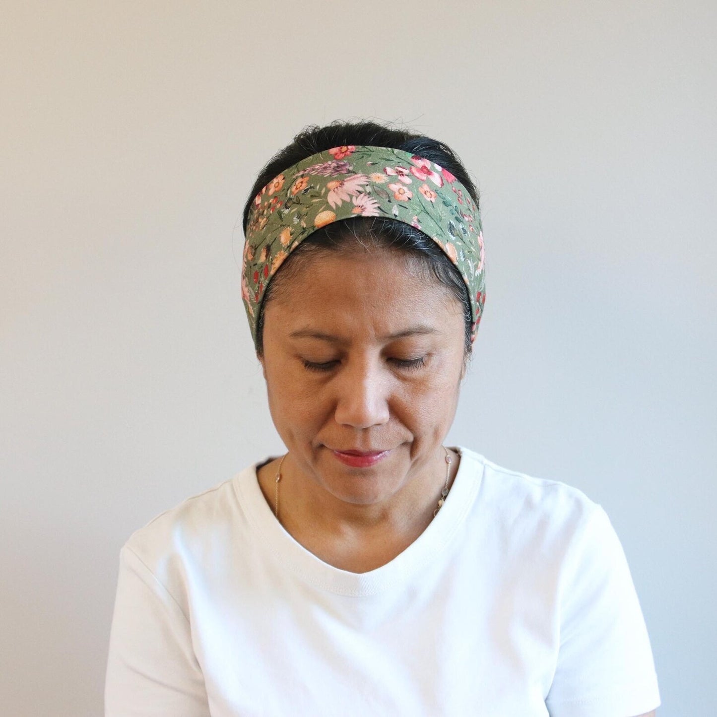 Woman wearing a floral headband against a plain background
