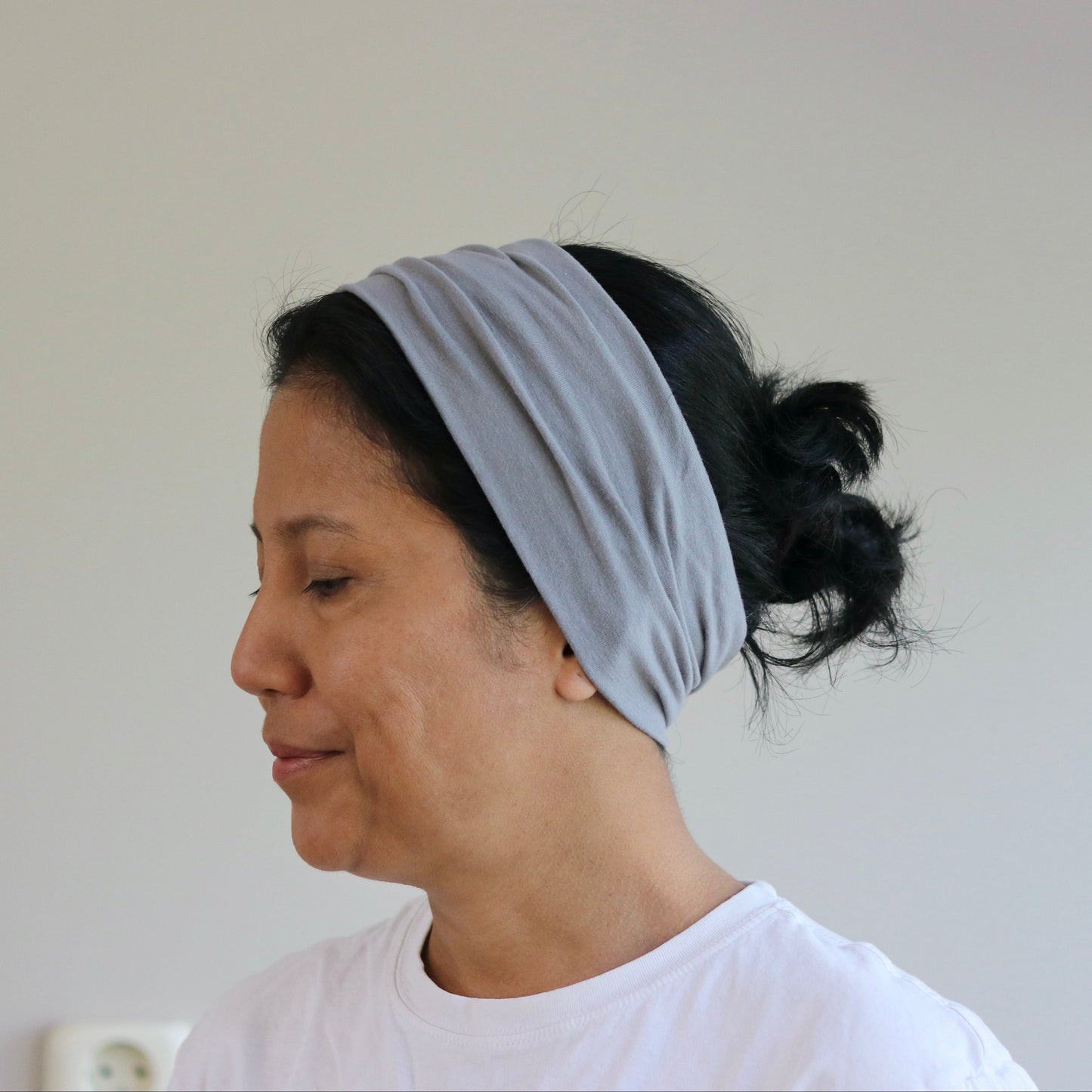 Woman wearing a light gray headband against a plain background