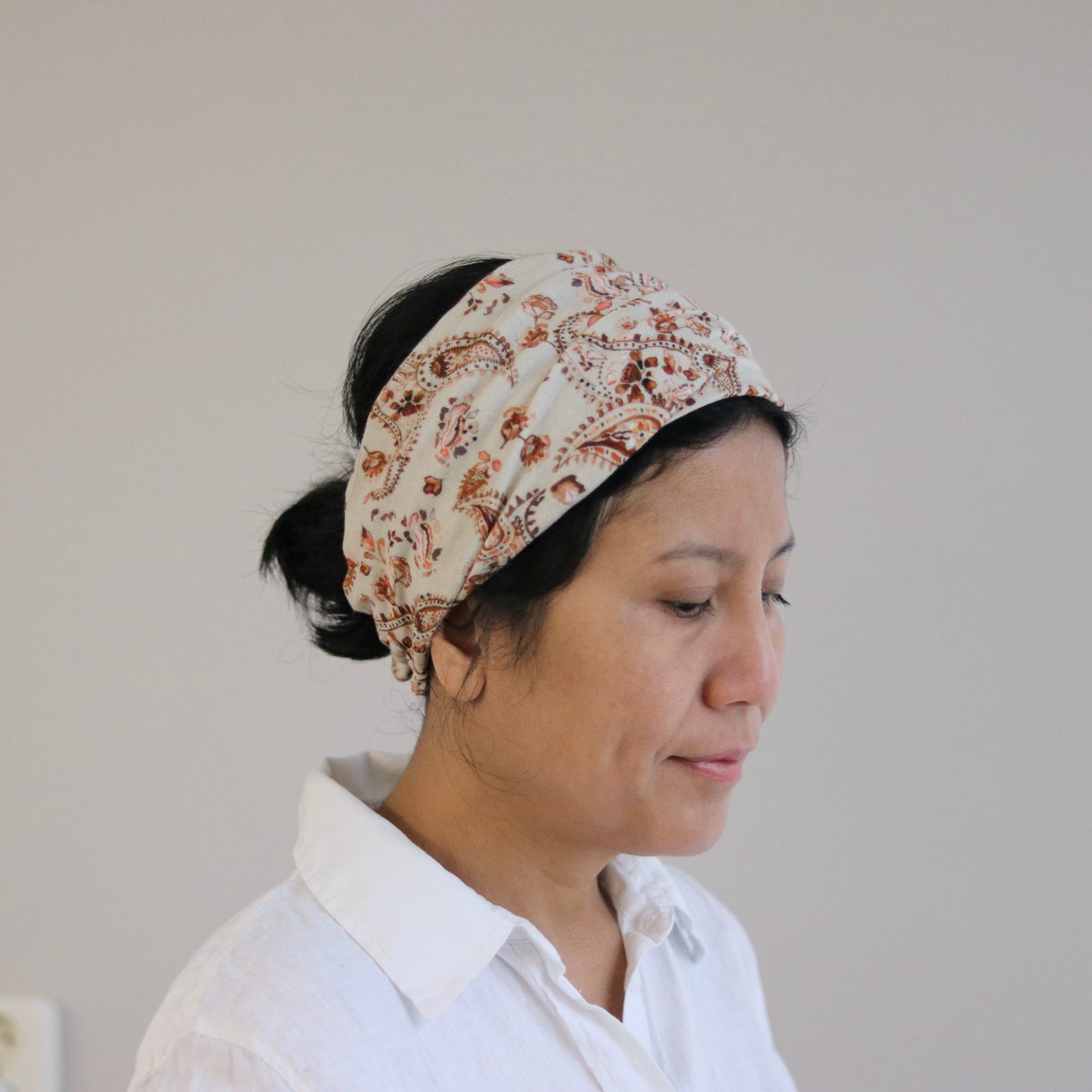 Woman wearing a floral headband against a plain background