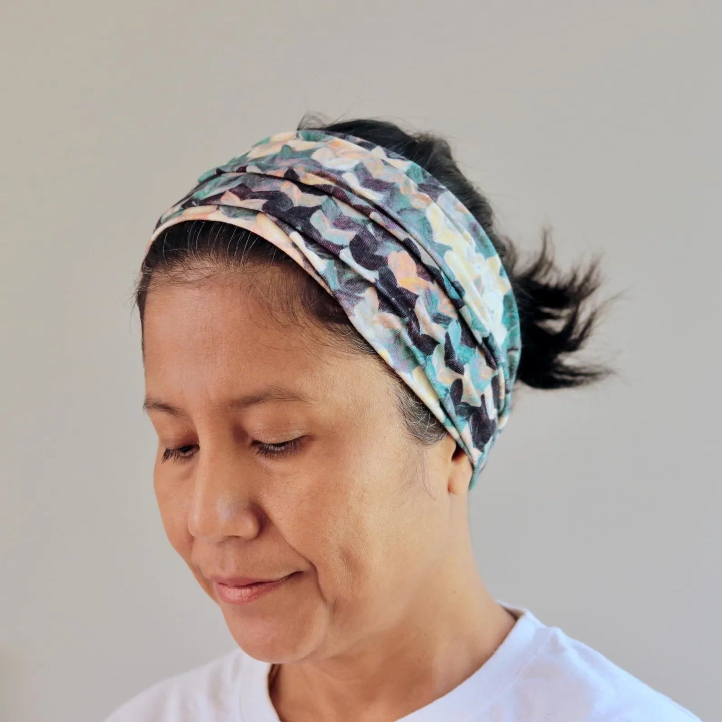 Woman wearing a patterned headband against a plain background