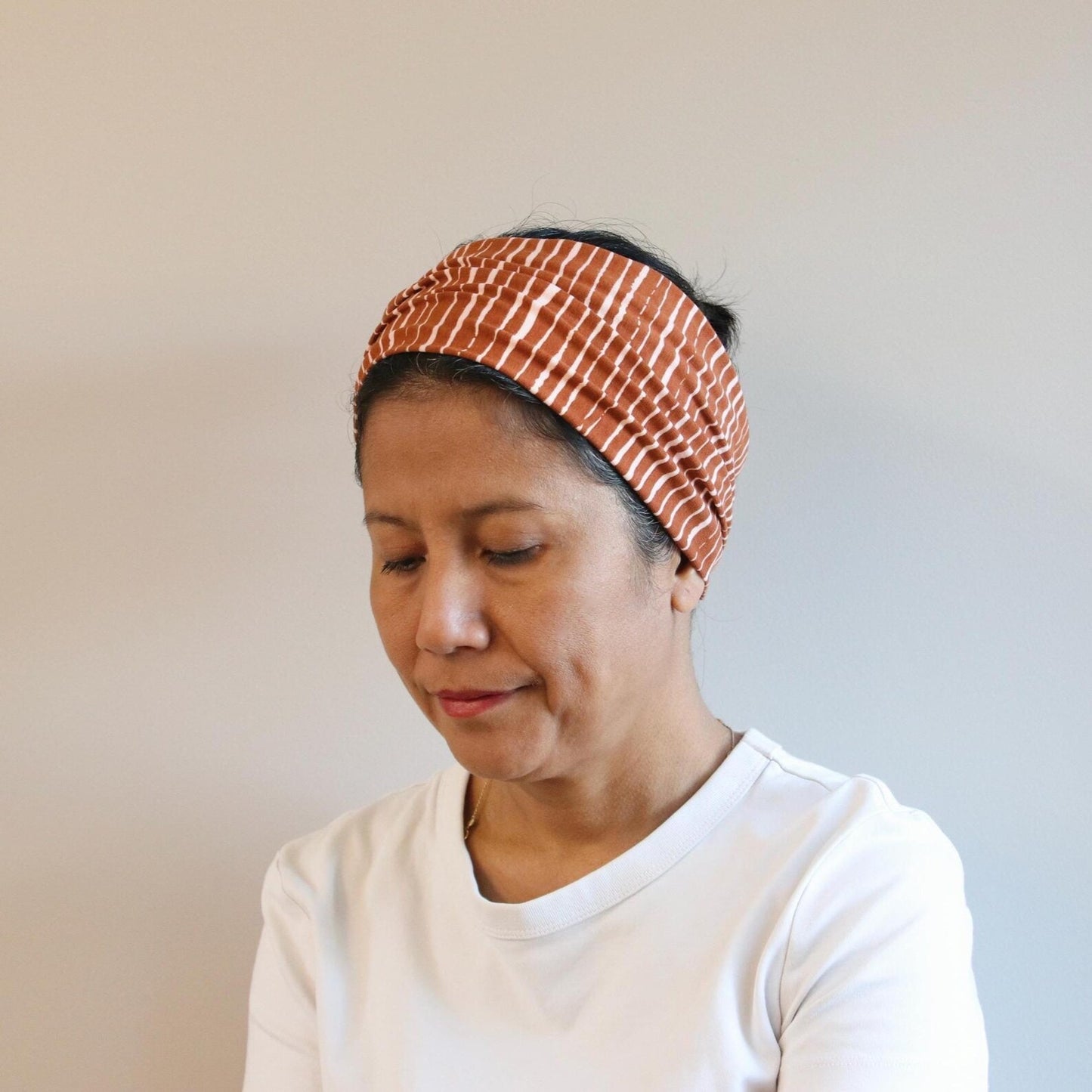 Woman wearing a patterned headband against a plain background