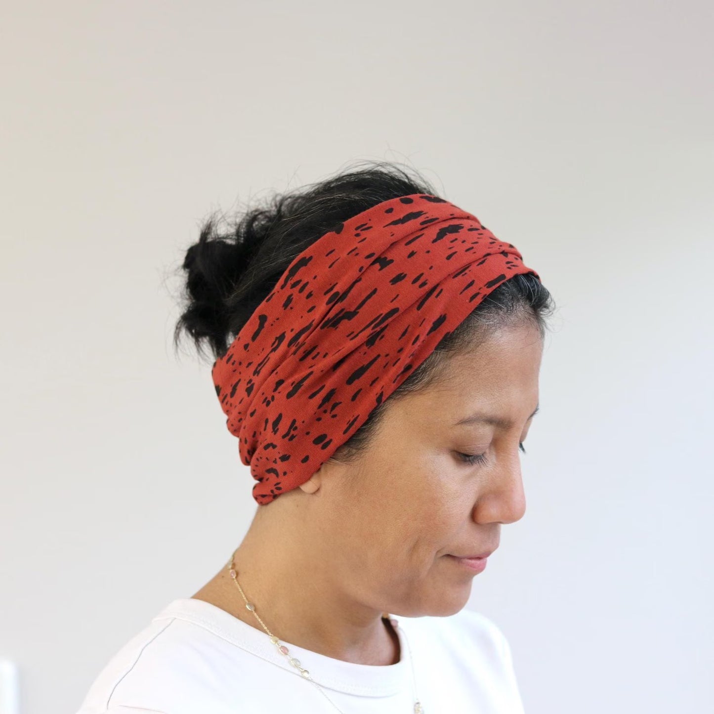 Person wearing a red headband with black patterns on a plain background
