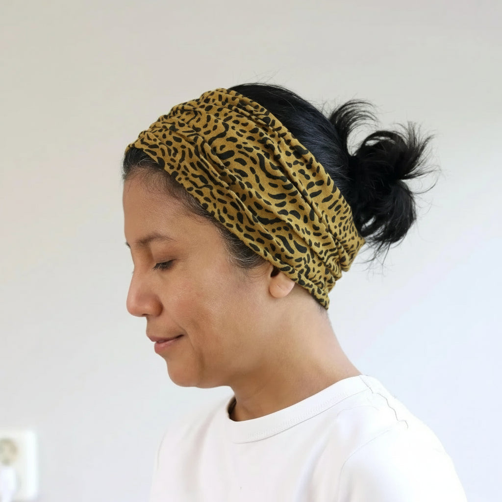Woman wearing a leopard print headband against a plain background