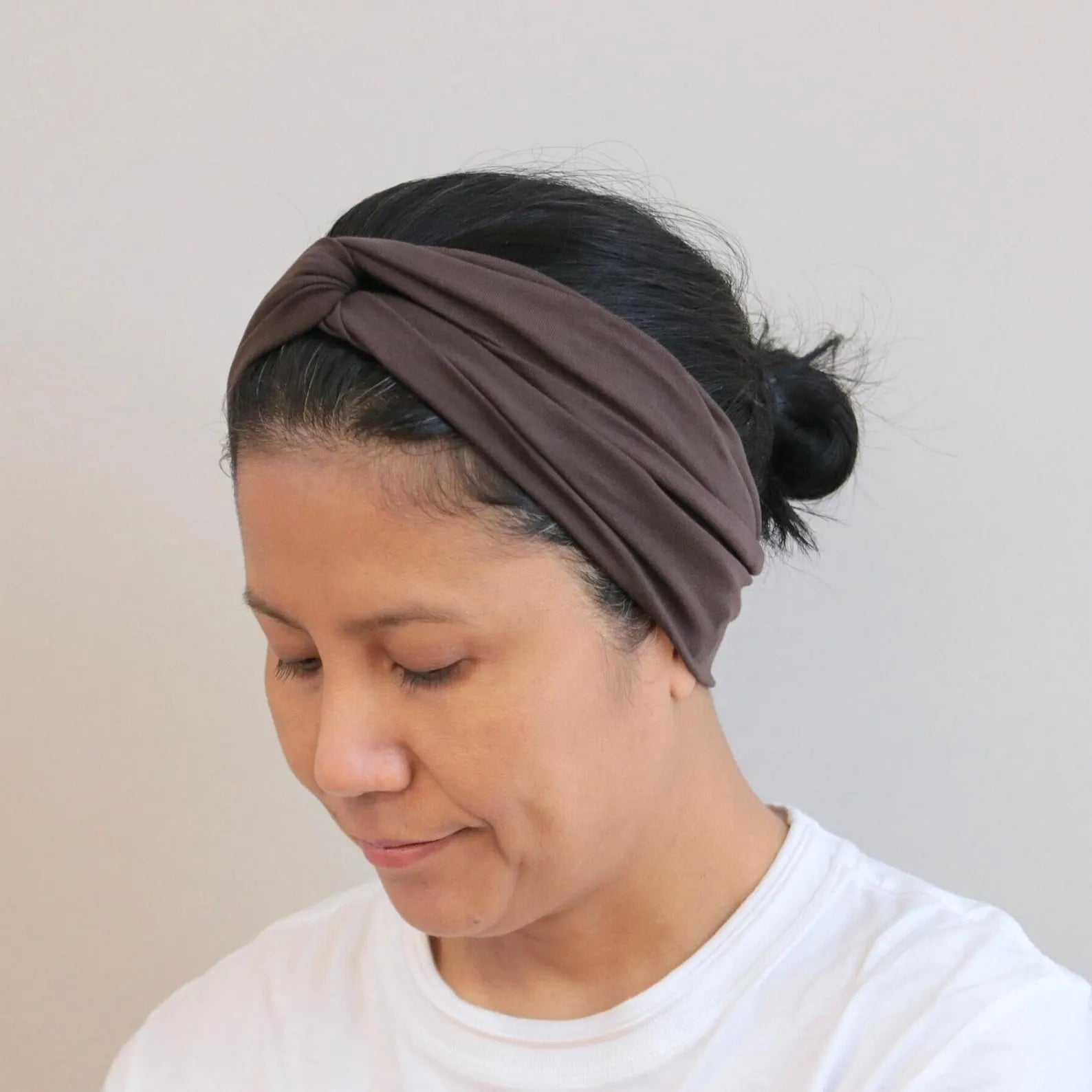 Woman wearing a brown headband against a plain background