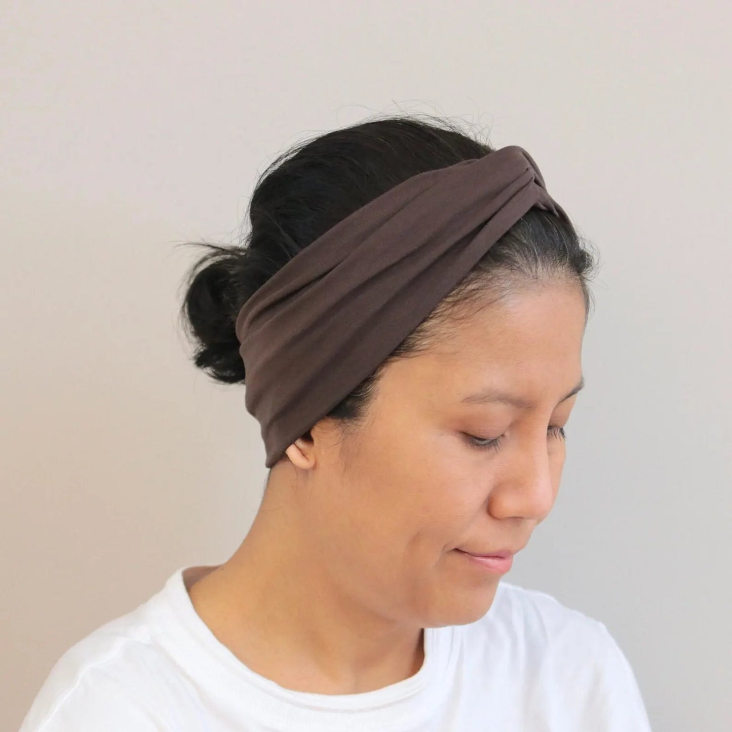 Woman wearing a brown headband against a plain background