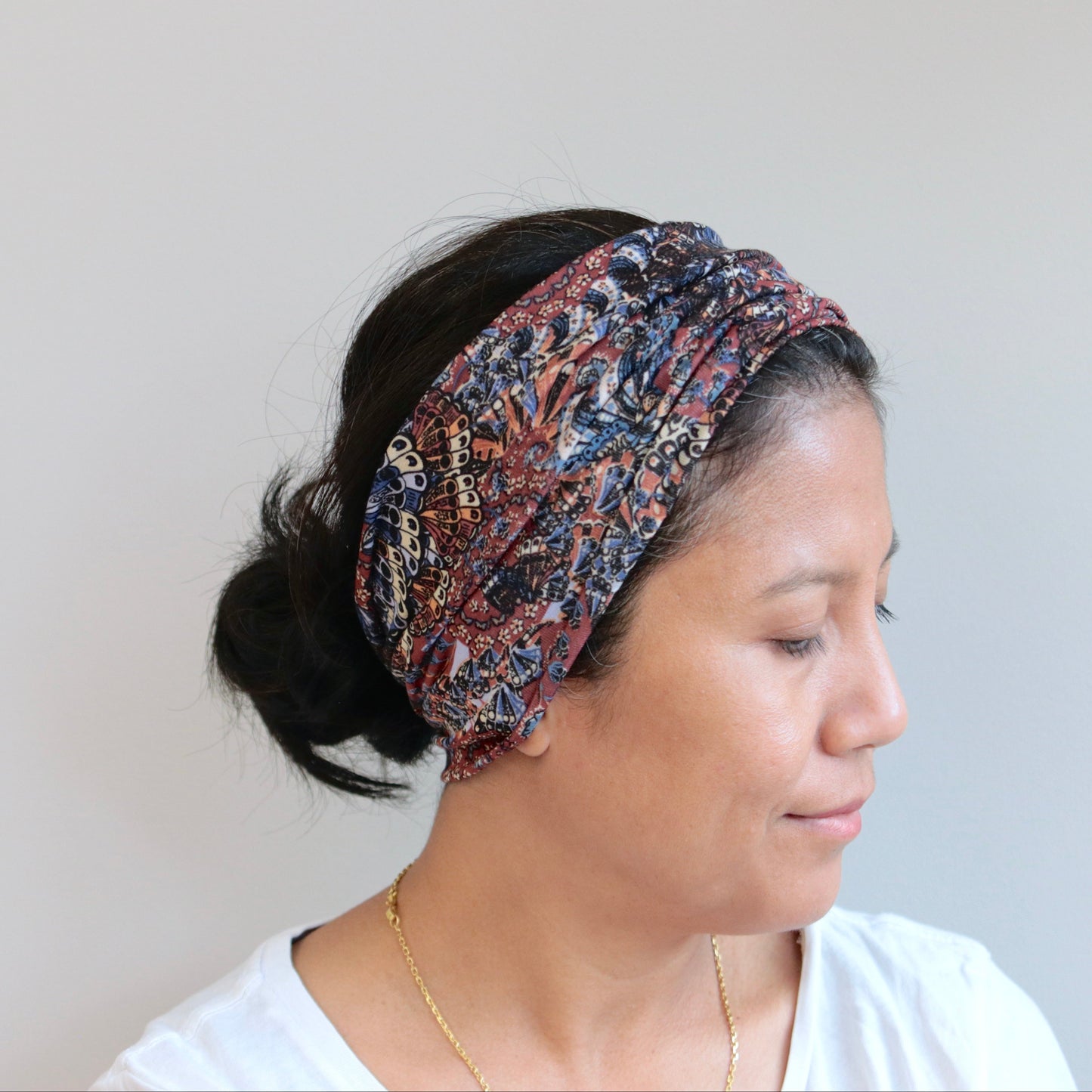Woman wearing a patterned headband against a plain background