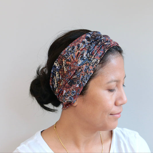 Woman wearing a patterned headband against a plain background