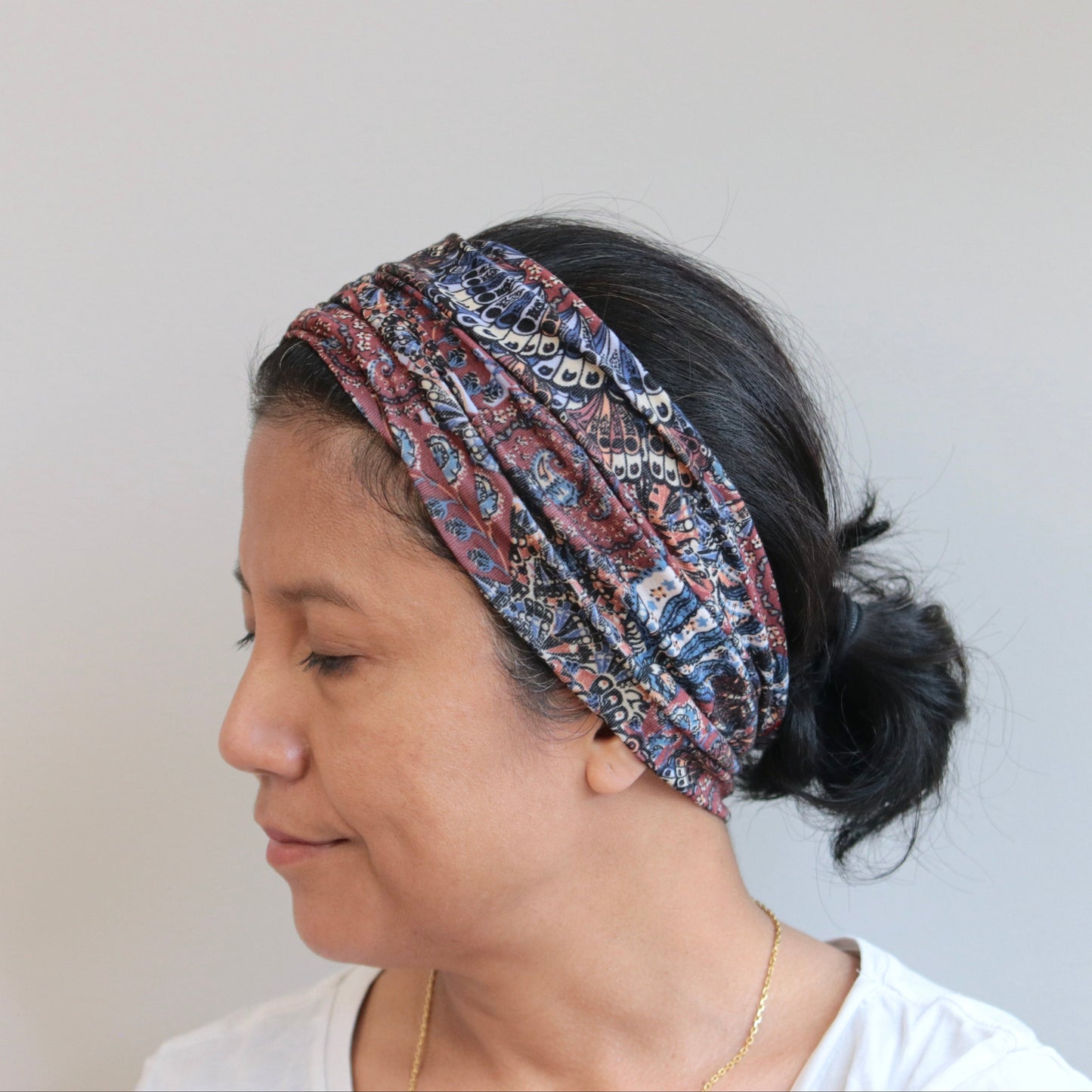 Woman wearing a patterned headband against a plain background