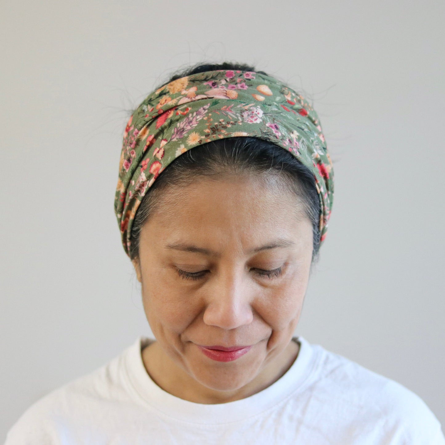 Woman wearing a floral headscarf against a plain background
