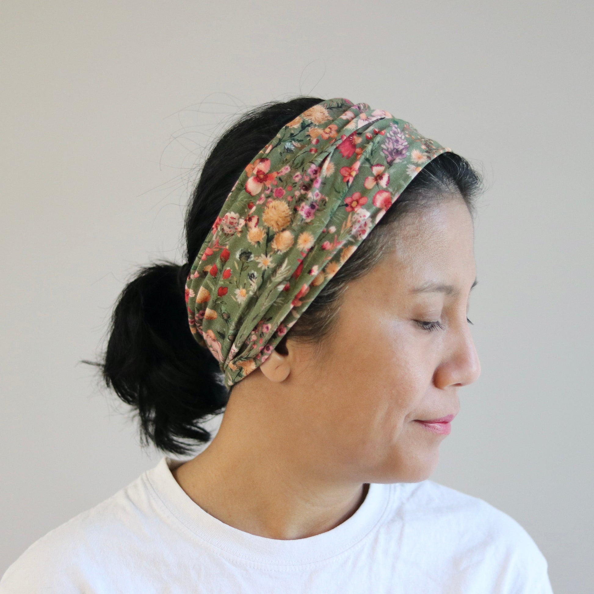 Woman wearing a floral headband against a plain background