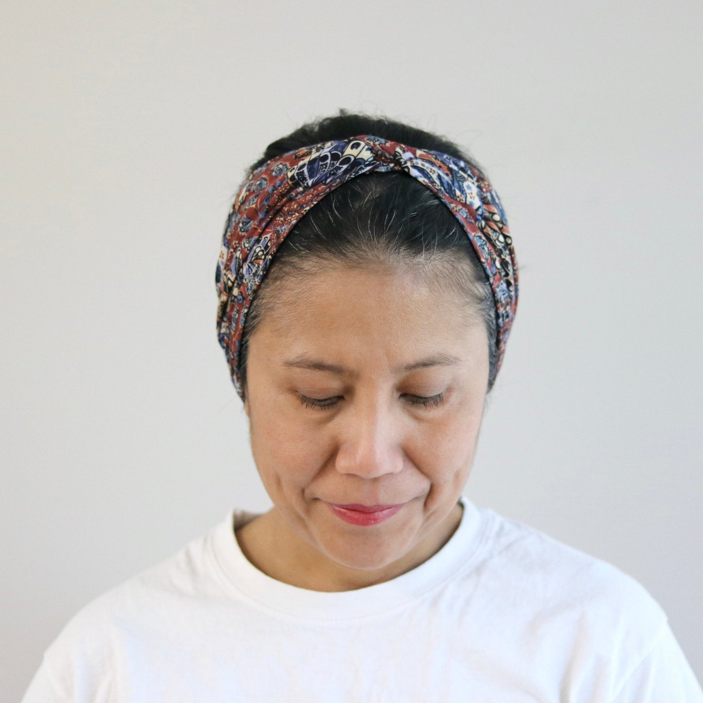 Woman wearing a patterned headband against a plain background