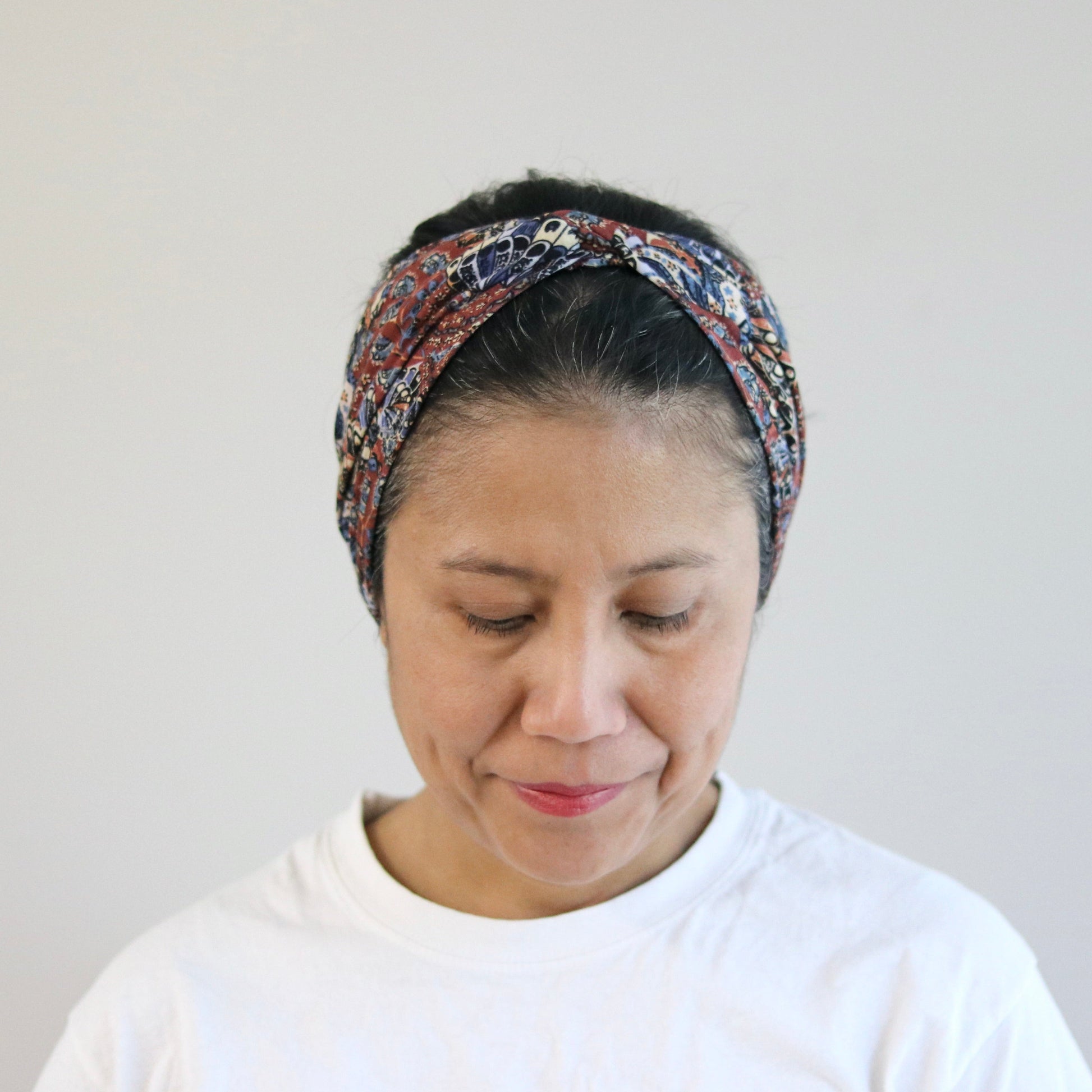 Woman wearing a patterned headband against a plain background
