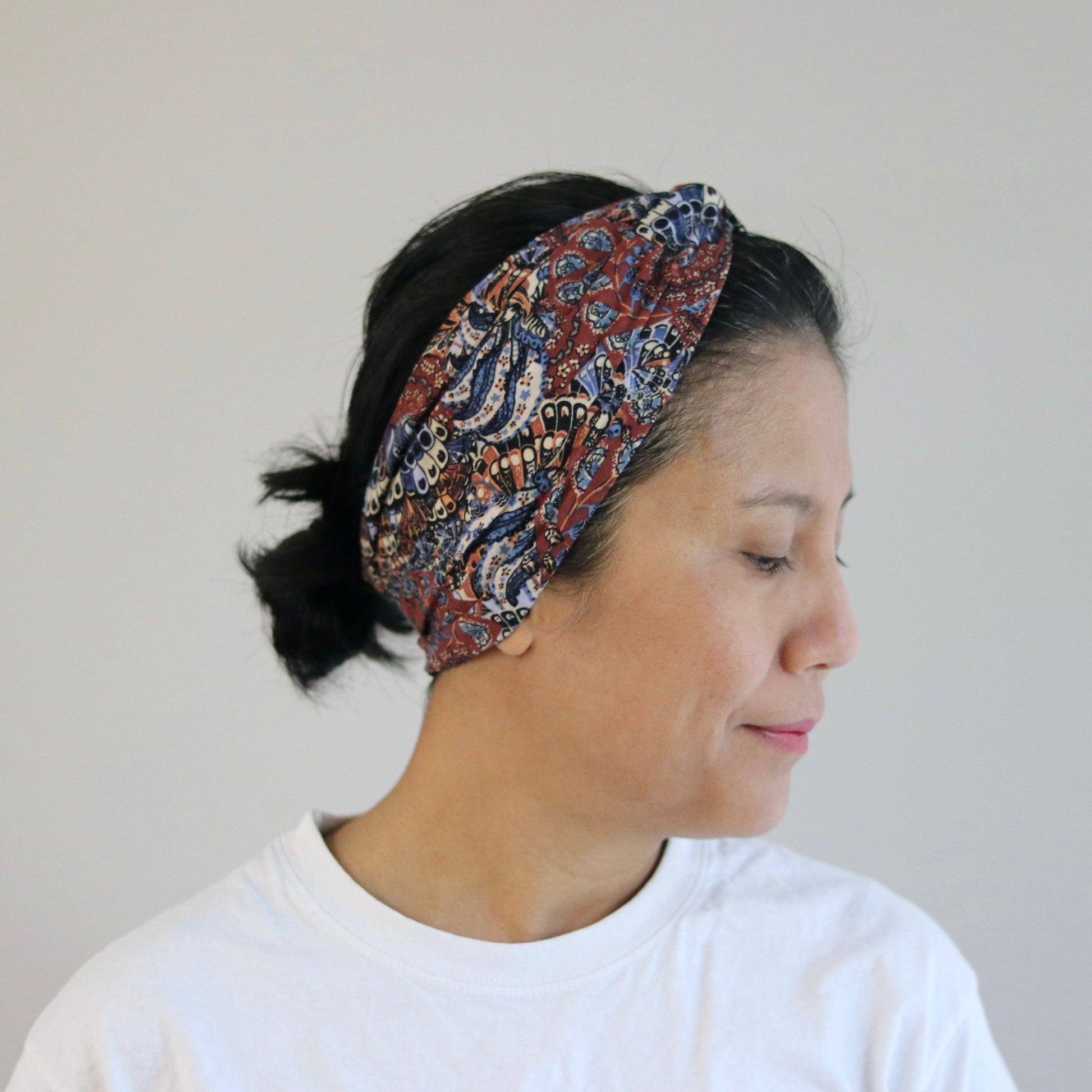 Woman wearing a patterned headband against a plain background