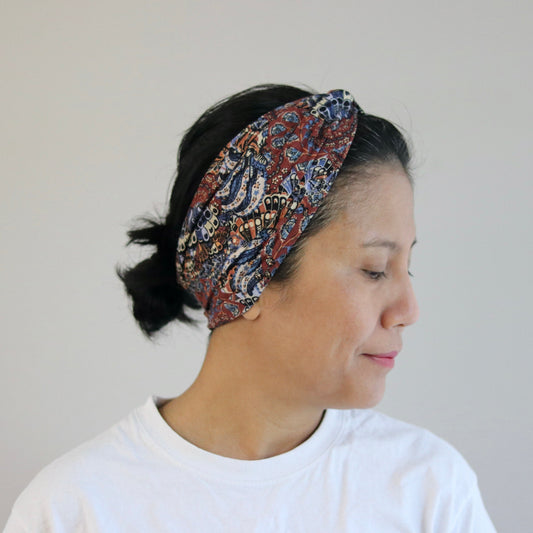 Woman wearing a patterned headband against a plain background
