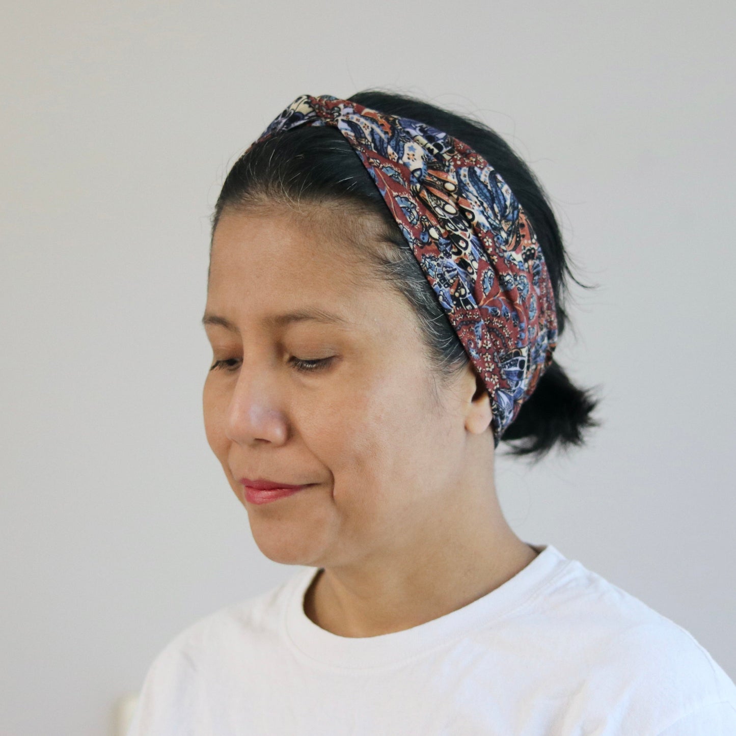 Woman wearing a patterned headband against a plain background