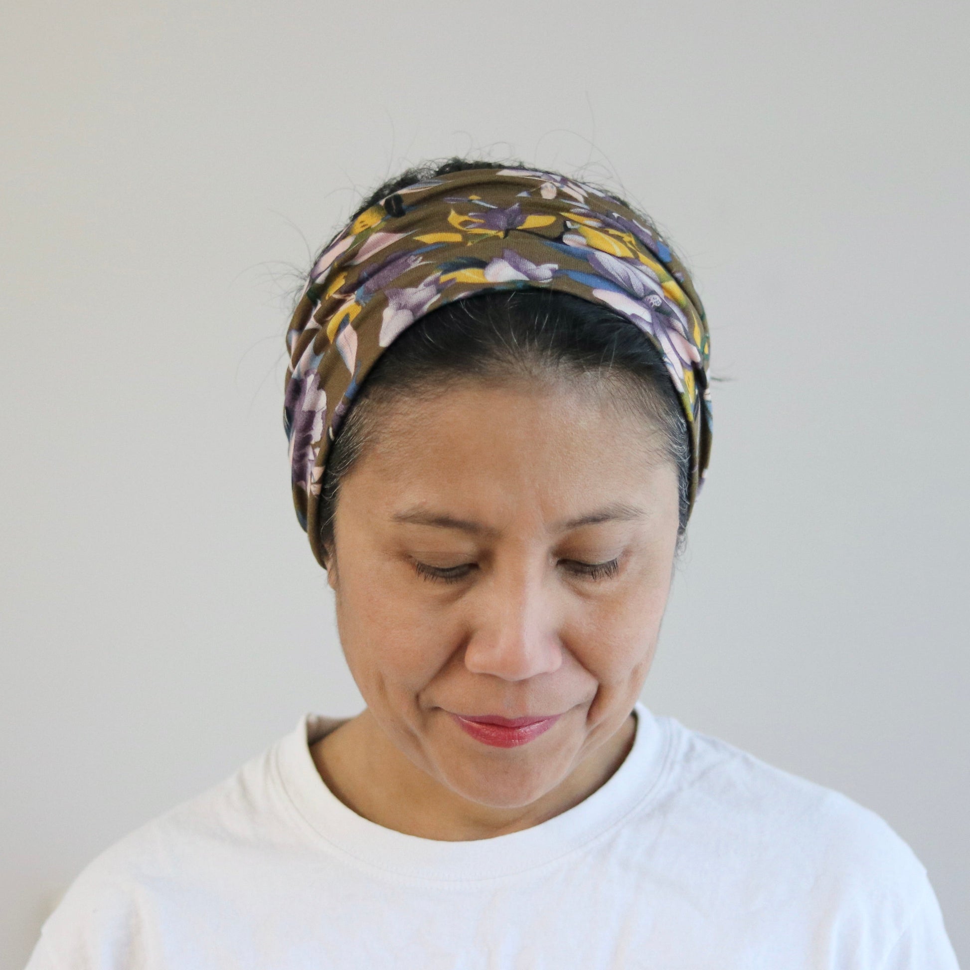 Woman wearing a patterned headscarf against a plain background
