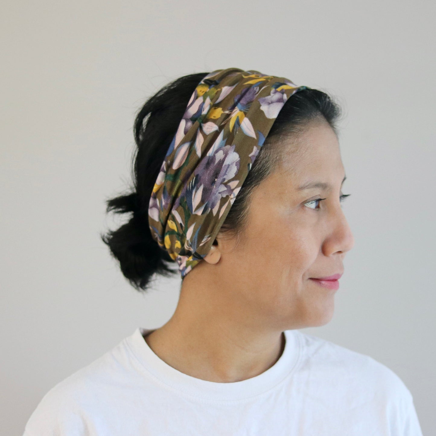 Woman wearing a floral headband against a plain background