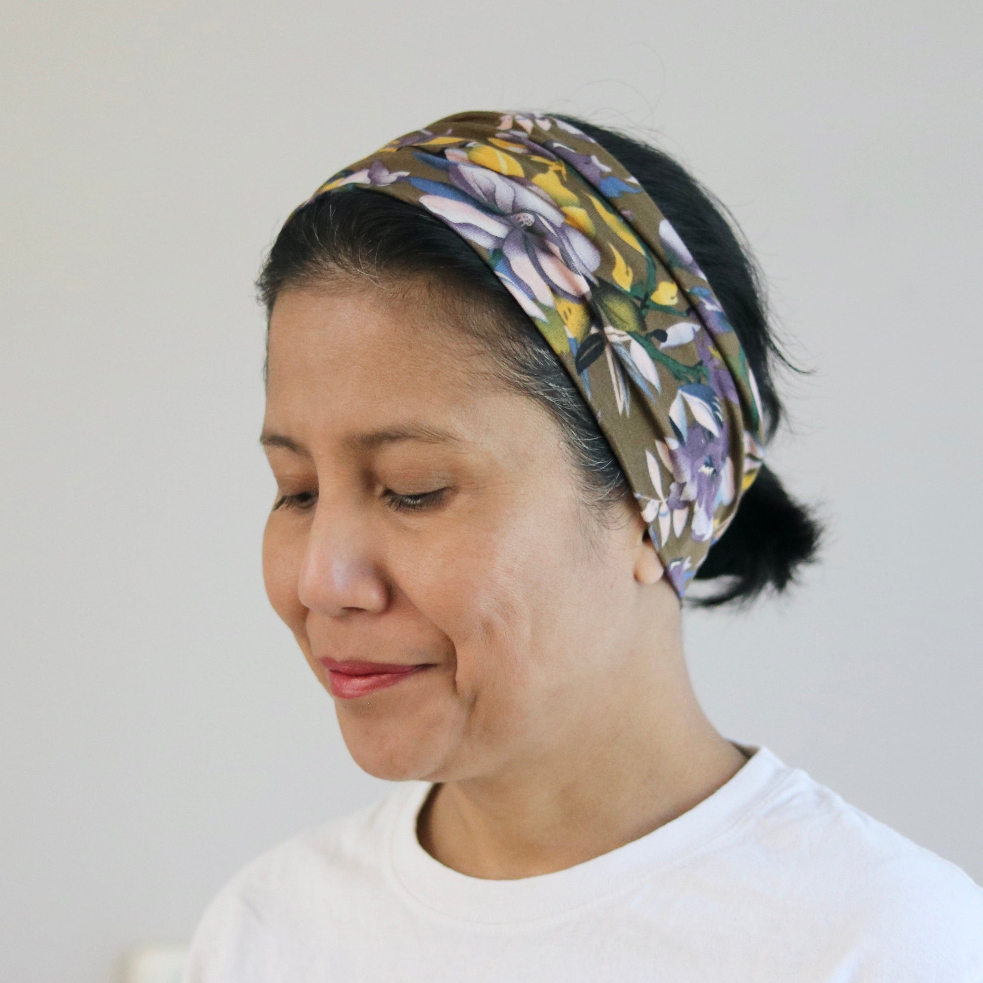 Woman wearing a patterned headscarf on a plain background