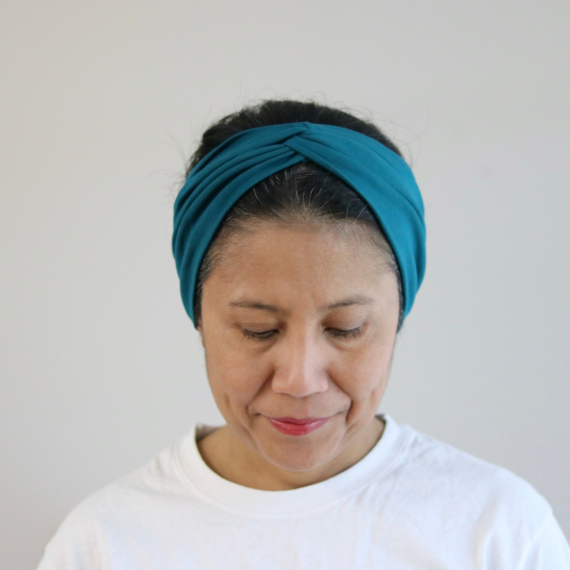 Woman wearing a blue headband against a plain background