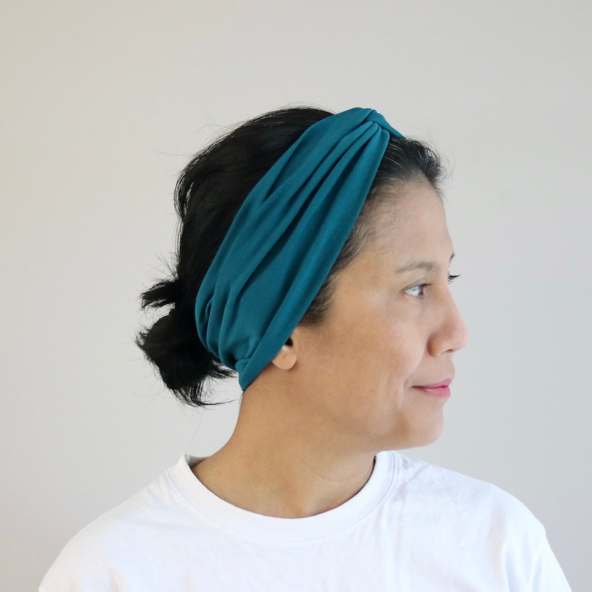 Woman wearing a teal headband against a plain background