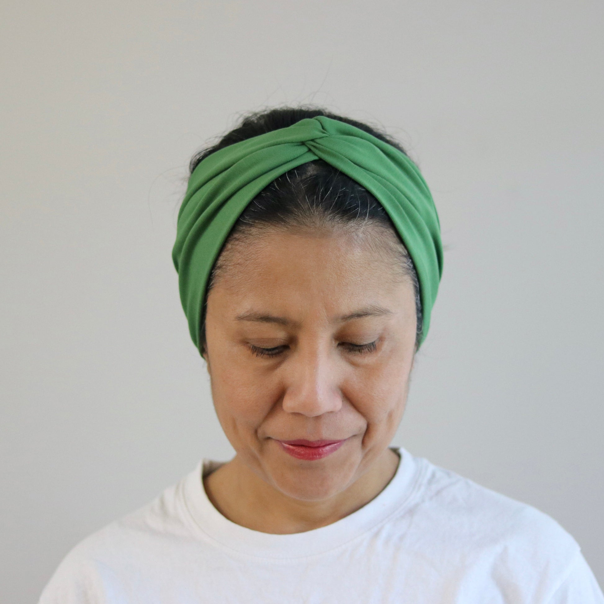Woman wearing a green headband against a plain background