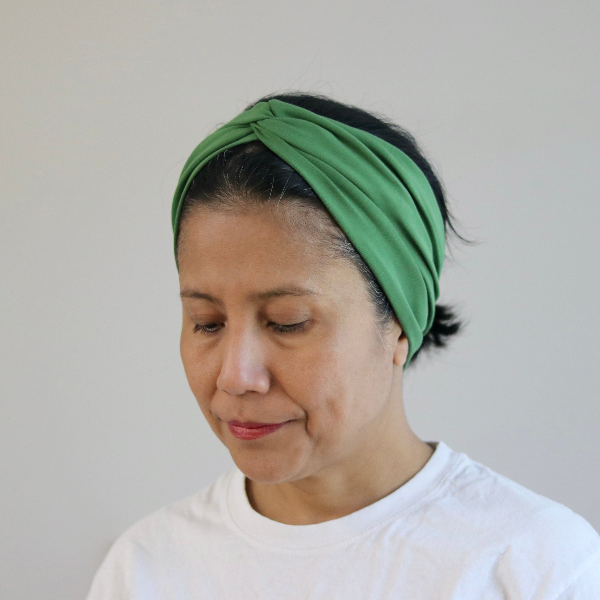 Woman wearing a green headband against a plain background