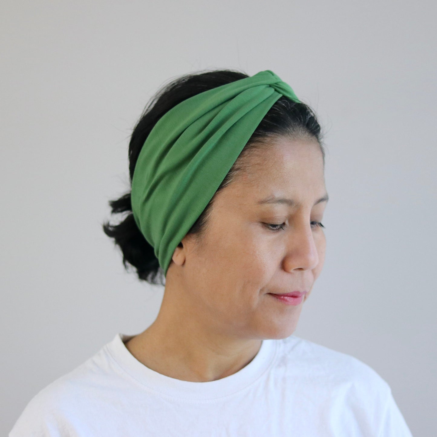 Woman wearing a green headband against a plain background
