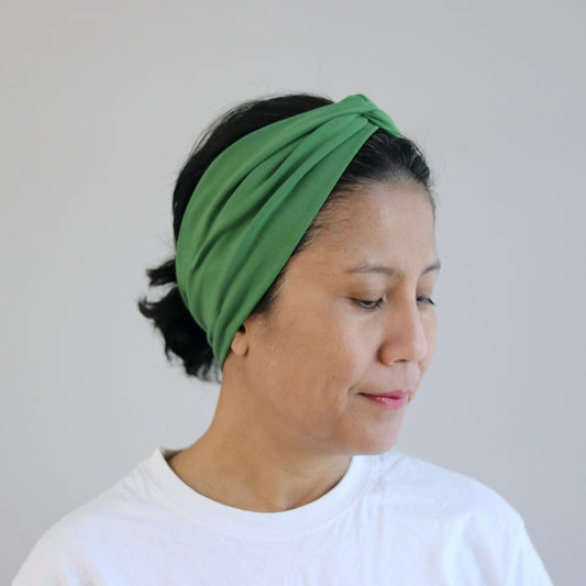 Woman wearing a green headband against a plain background