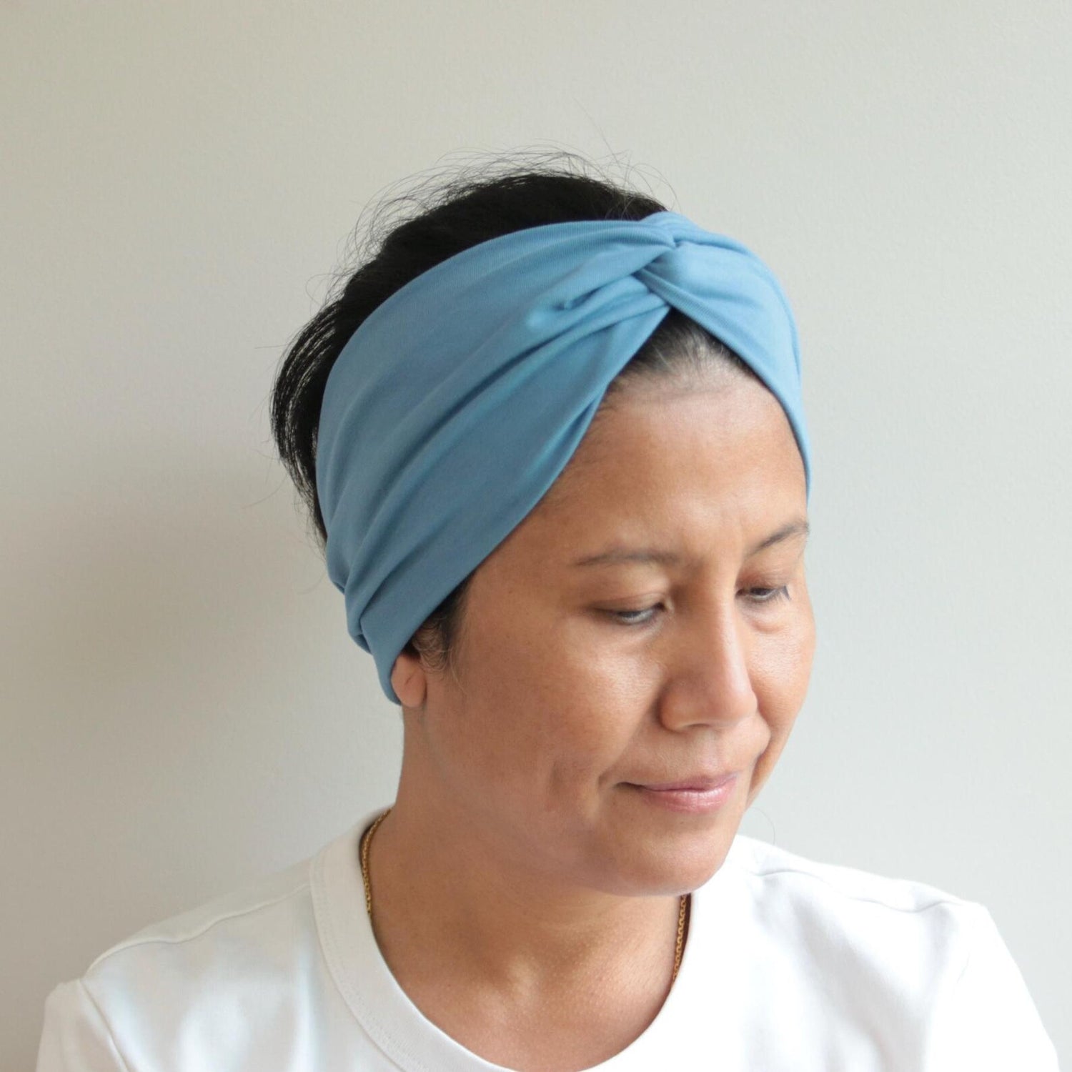 Woman wearing a blue headband against a plain background