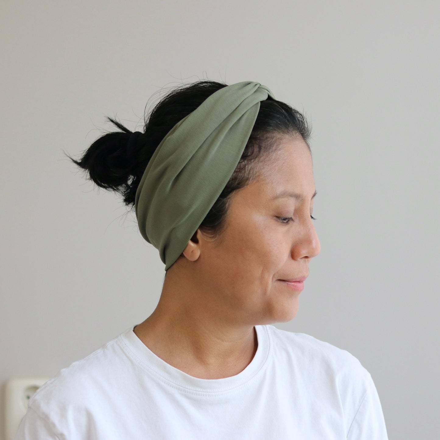 Woman wearing a green headband against a plain background