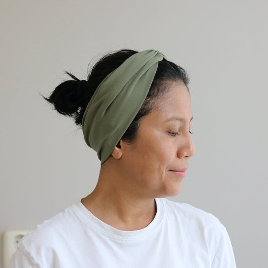 Woman wearing a green headband against a plain background