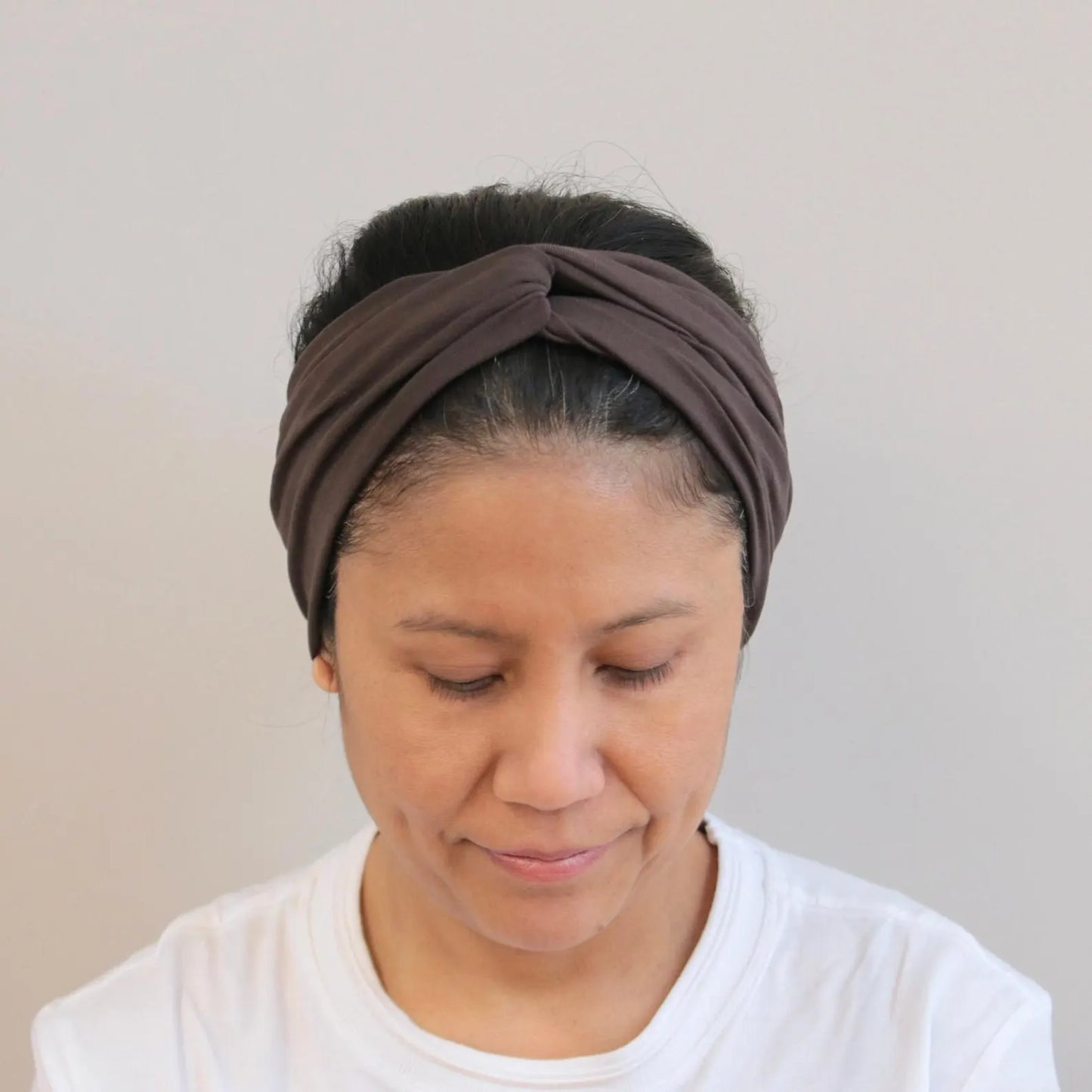 Woman wearing a brown headband against a plain background