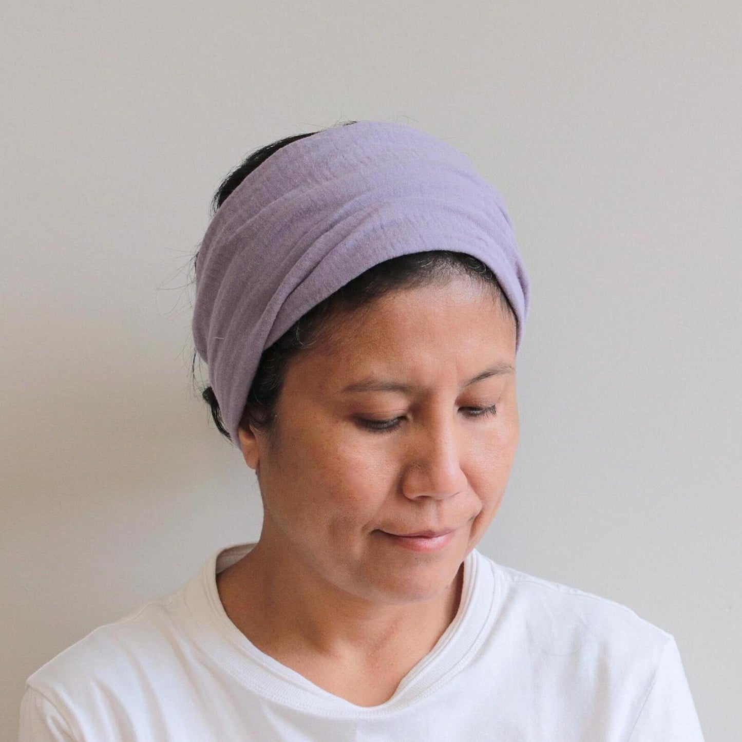 Woman wearing a purple headband against a plain background