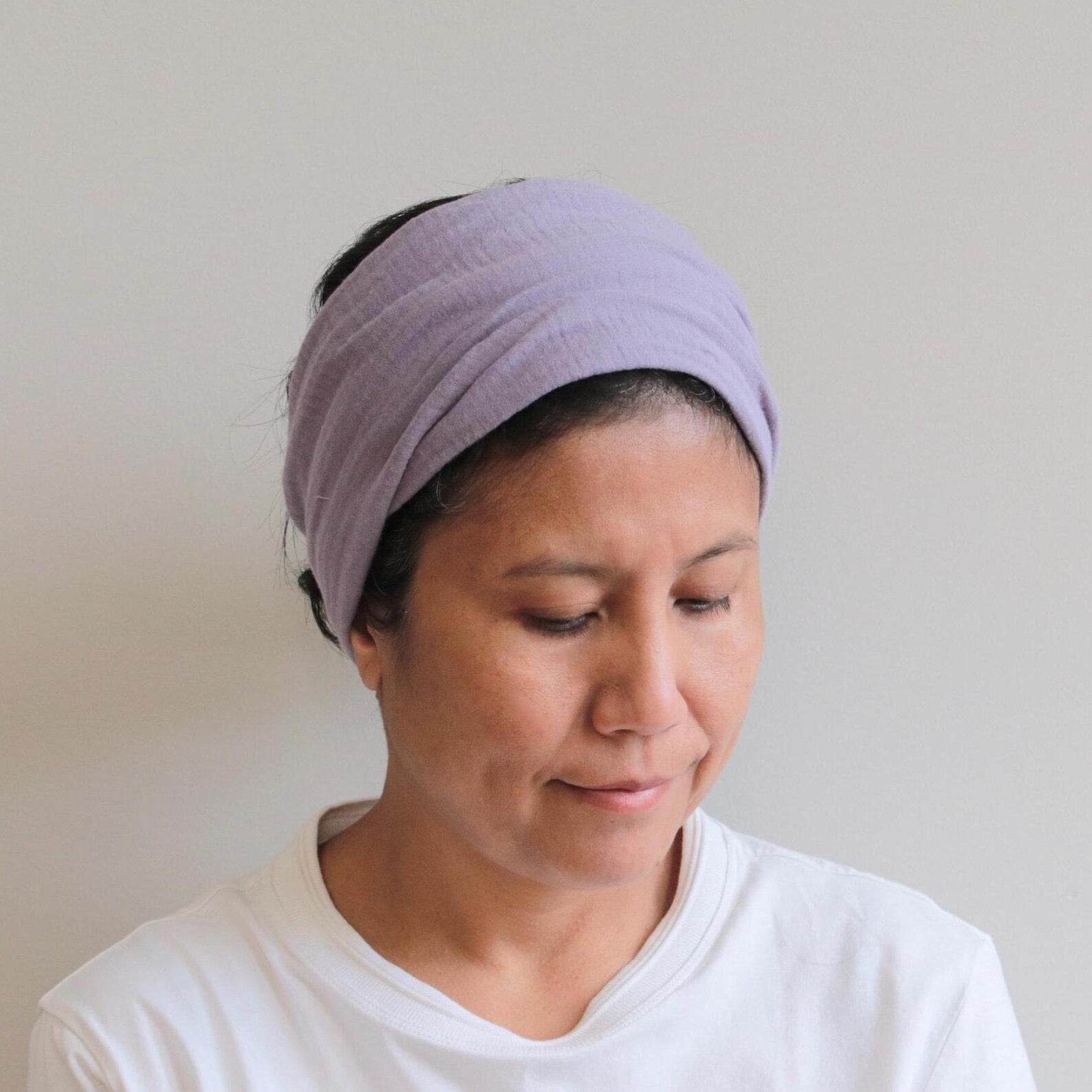Woman wearing a purple headband against a plain background