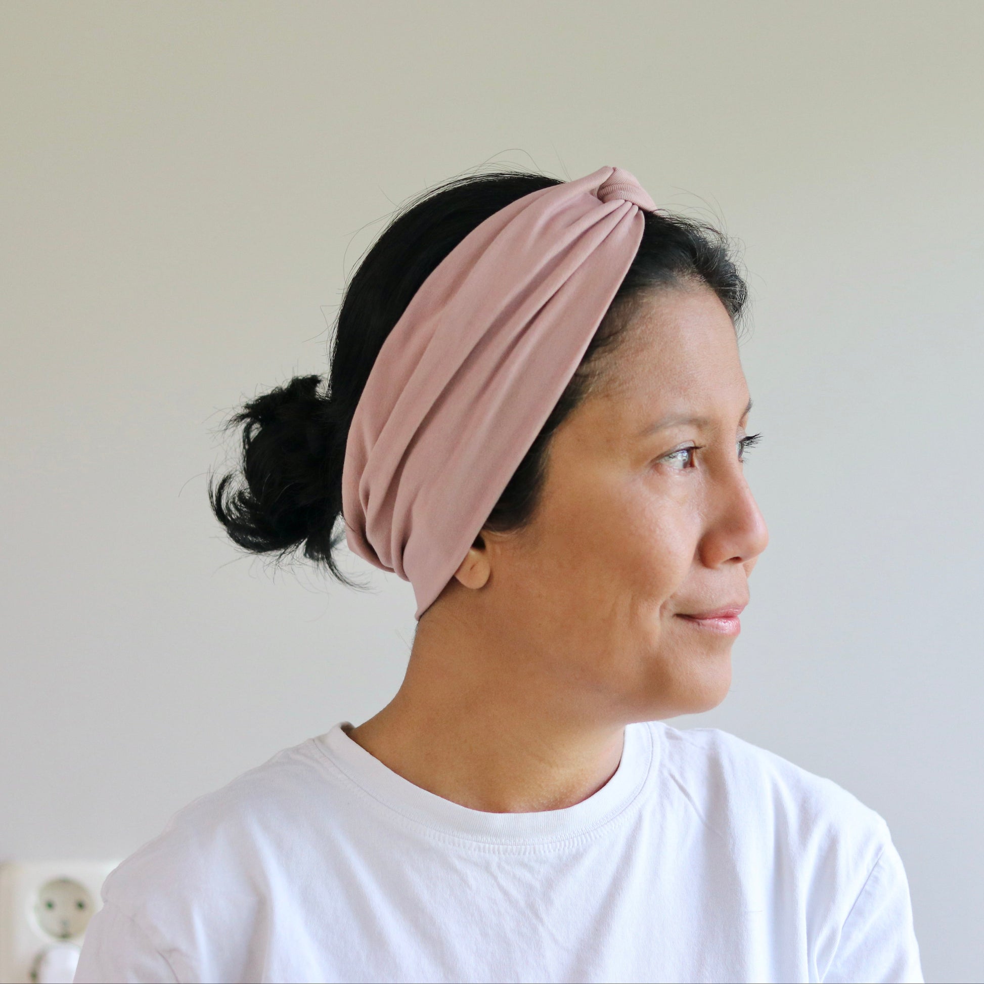 Woman wearing a pink headband against a plain background