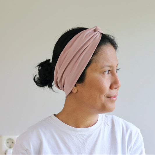 Woman wearing a pink headband against a plain background