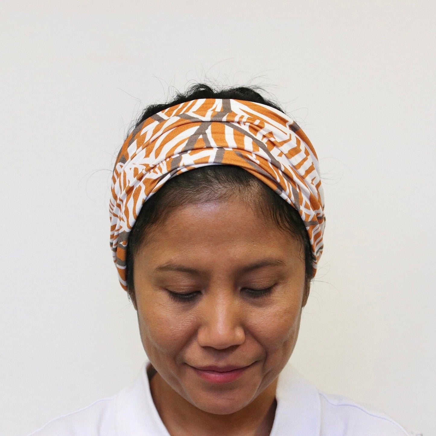 Person wearing a patterned headband against a plain background