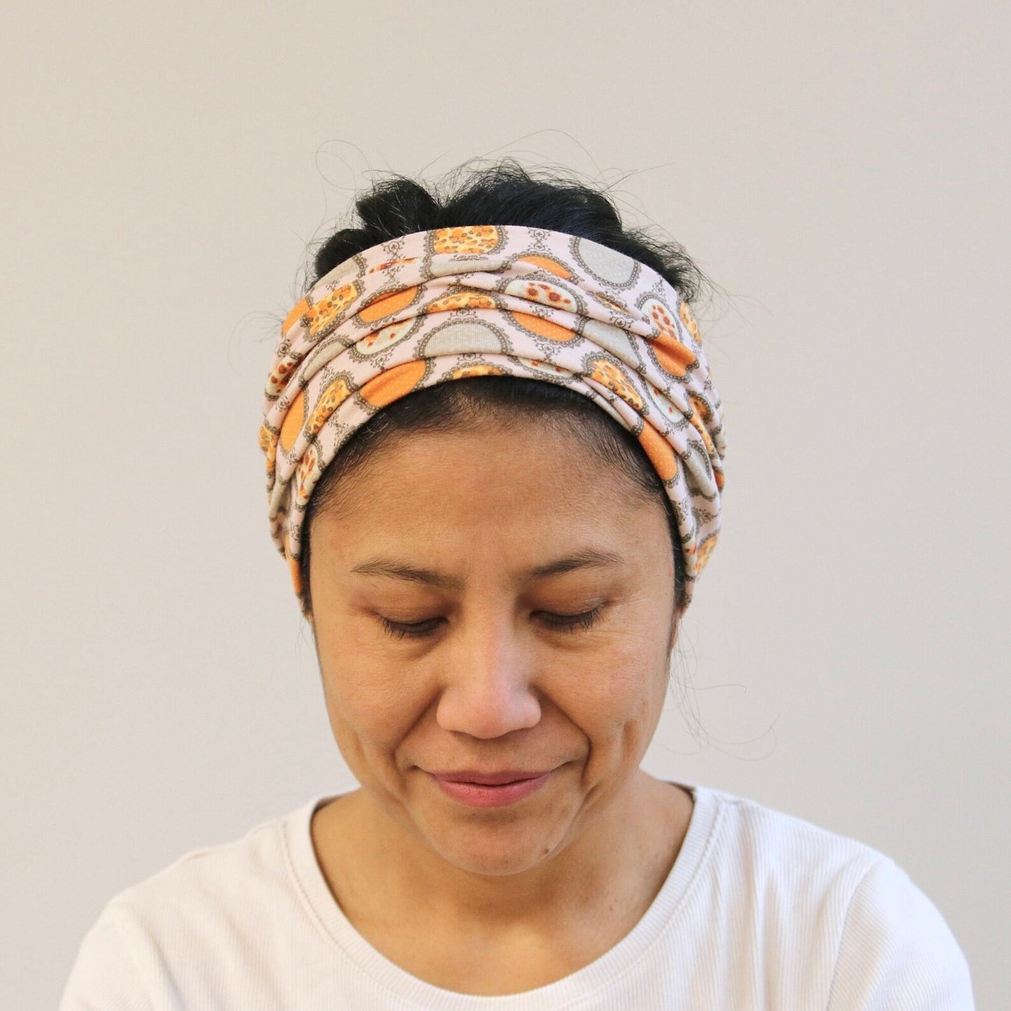 Woman wearing a patterned headband against a plain background