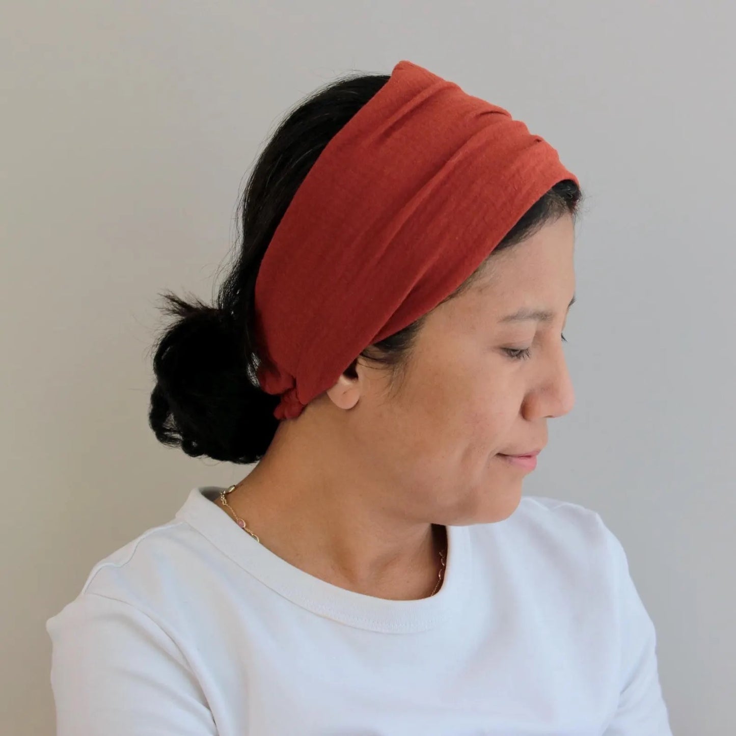Woman wearing a red headband against a plain background