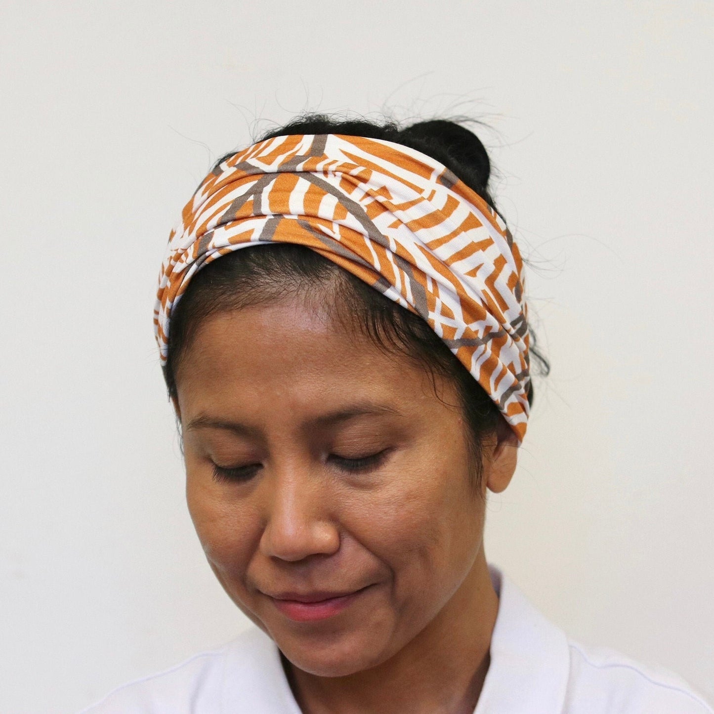 Woman wearing a patterned headband against a plain background