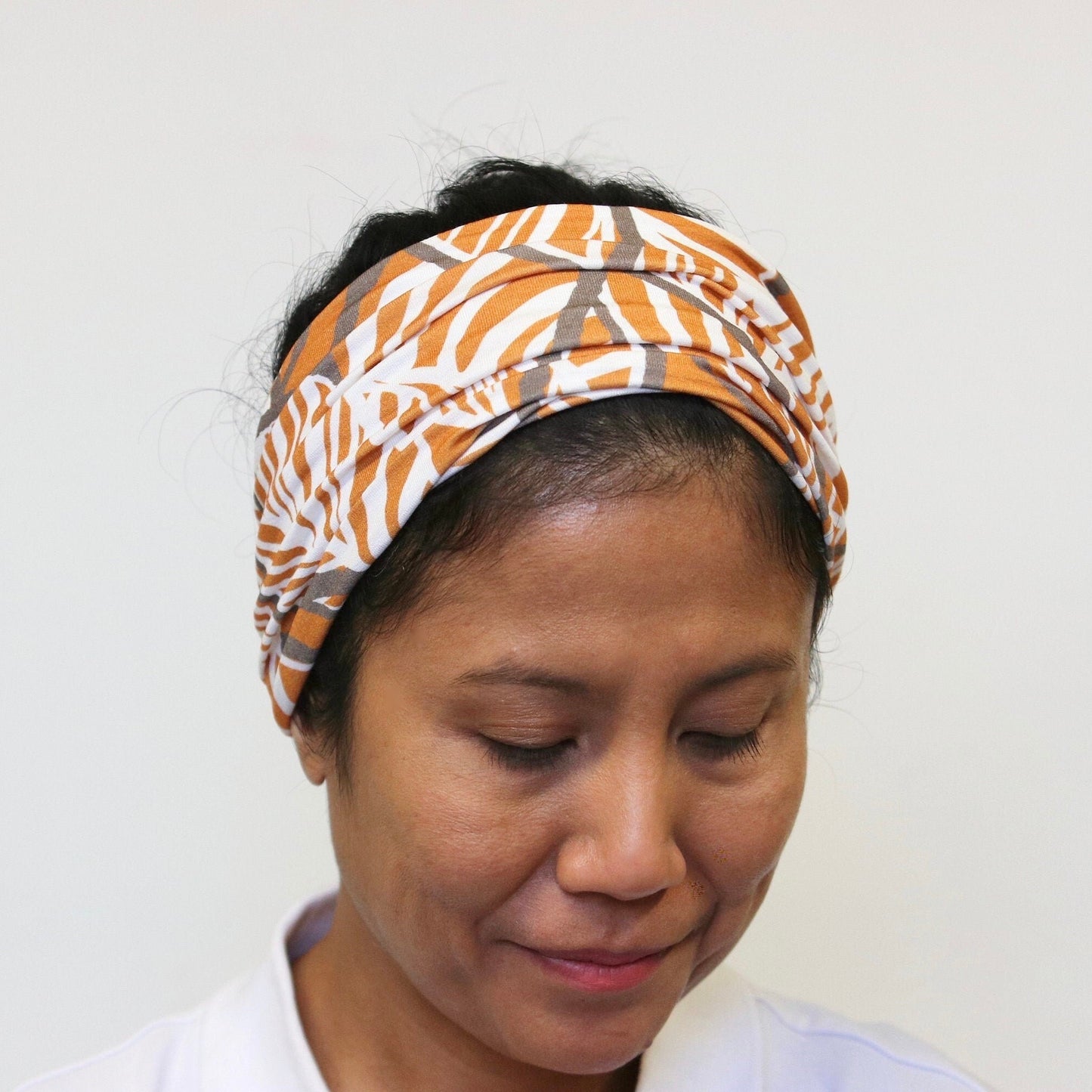 Person wearing a patterned headband against a plain background