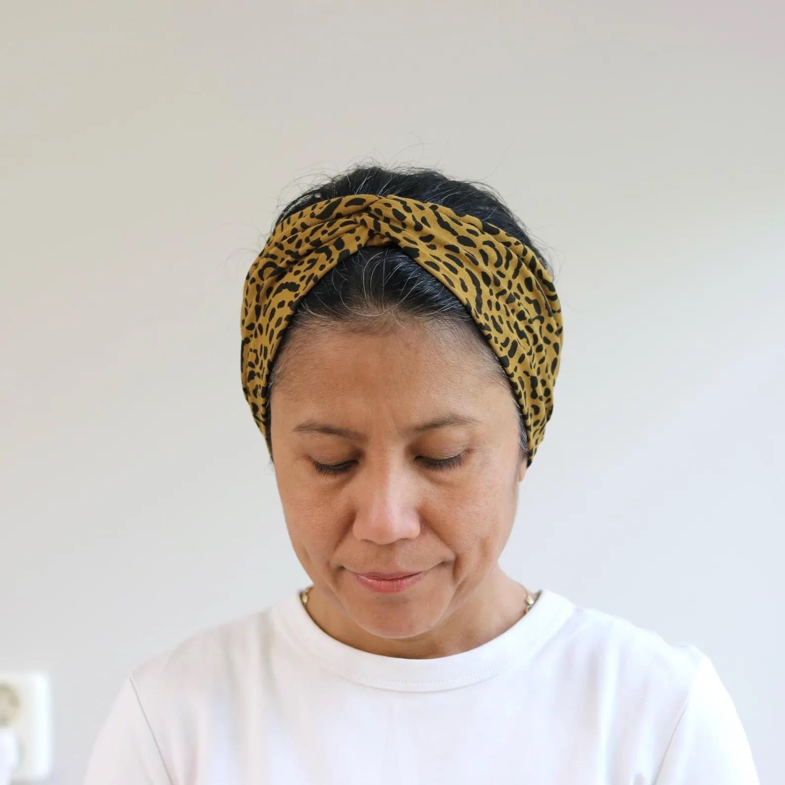 Woman wearing a leopard print headband against a plain background