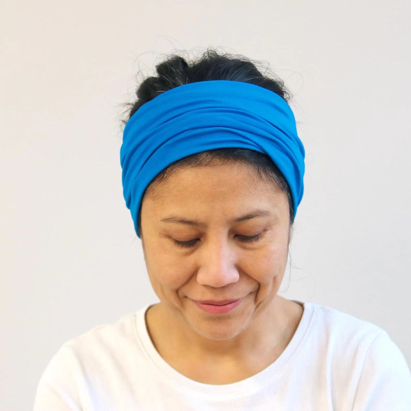 Woman wearing a blue headband against a plain background