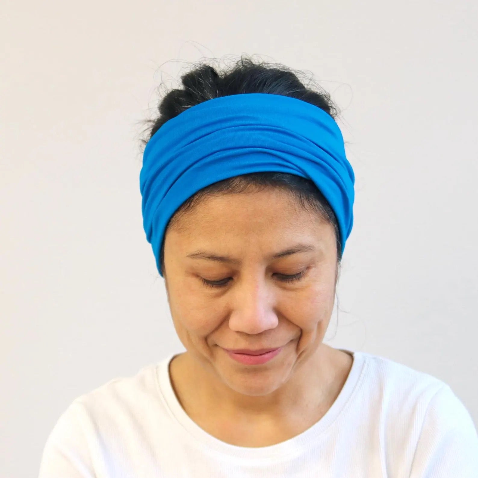 Woman wearing a blue headband against a plain background