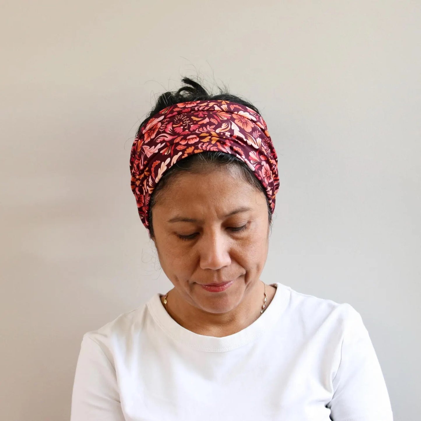 Woman wearing a patterned headband against a plain background